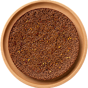 Brown coarse spice powder with yellow mustard seeds in a round wooden bowl.